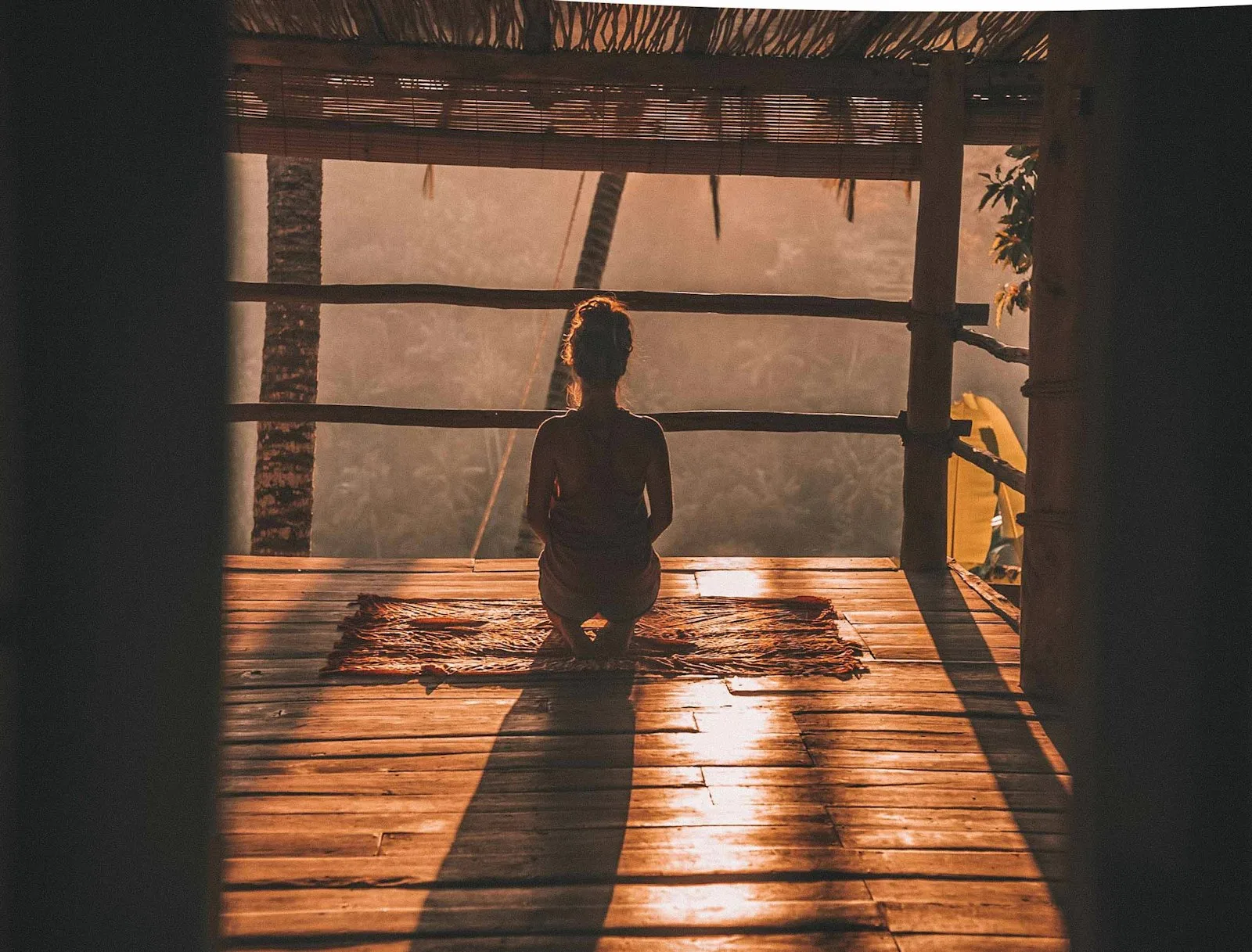 Guest meditating on a wooden retreat deck at sunset